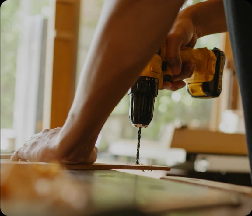 Close-up of a person’s hands using a yellow power drill